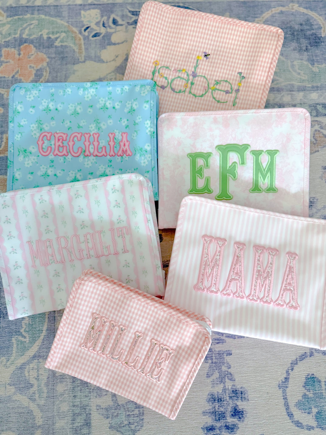 Colorful personalized pouches featuring names like EFM, Mama, and Cecelia, showcasing unique TRVL design.