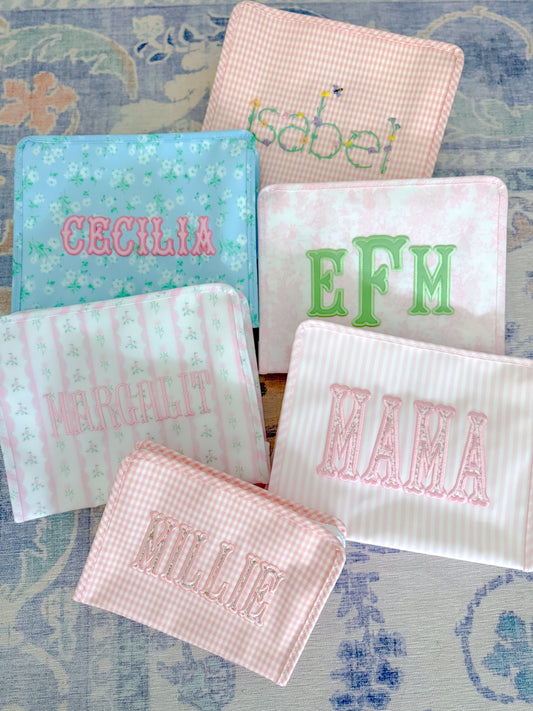 Colorful personalized pouches featuring names like EFM, Mama, and Cecelia, showcasing unique TRVL design.
